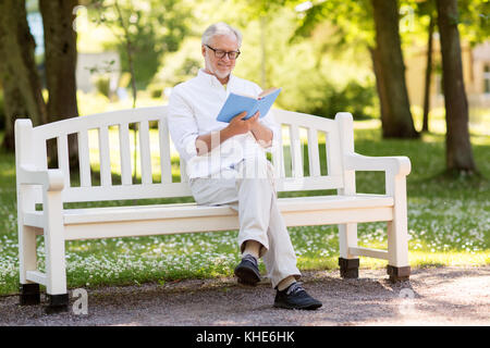 Gerne älterer Mann lesen Buch im Sommer Park Stockfoto