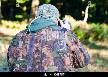 Richmond Park, London. Männliche Fotograf tragen Camouflage fotografieren Red Deer. Stockfoto