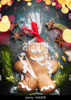 Gingerbread Man Cookie in Zellophan Beutel verpackt und mit festlichen Band auf vintage Hintergrund mit Urlaub bokeh Beleuchtung gebunden, Ansicht von oben Stockfoto