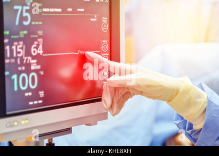 Arzt Hand berühren auf elektrokardiogramm zeigt Herzfrequenz des Patienten in der Notaufnahme im Krankenhaus mit unscharfen Hintergrund Stockfoto