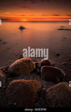 Dämmerung Glühen am Horizont über den Lake Huron, Michigan mit großen Strand Felsen, United States, östlichen Nordamerika Stockfoto