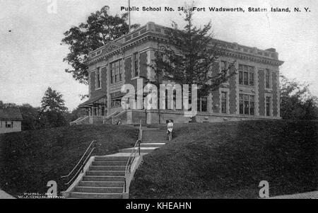 Eine Postkarte von einem Foto der öffentlichen Schule Nr. 34 in Fort Wadsworth, das zweistöckige Steingebäude befindet sich auf dem Gipfel eines kleinen, grasbedeckten Anstiegs, eine Steintreppe mit Handläufen führt zum Gebäude, eine Person kann gesehen werden, wie sie auf der Treppe nebenbei posiert, State Island, New York, 1900. Aus der New York Public Library. Stockfoto