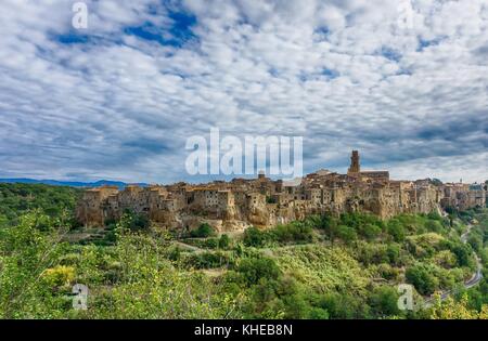 Horizontale Foto der antiken Stadt pitigliano in der Toskana Italien. Die Stadt ist aus Tuffstein gebaut. Straße, die in die Stadt zwischen Bäumen geht und Stockfoto