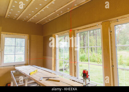 Bauarbeiten, Abschluss der Arbeiten in einem Holzhaus und Windows Installation mit der Ebene der Laserlinie Stockfoto