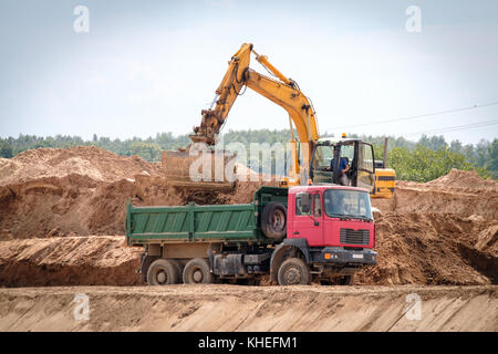 Bagger lädt die Masse im Fahrzeug Stockfoto