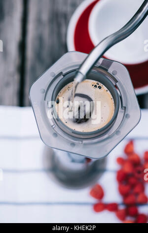 Köstliche morgen frisch gebrühten Filterkaffee im rustikalen Holztisch Hintergrund. Prozess der alternative Kaffee mit umgekehrten Methode brau Stockfoto