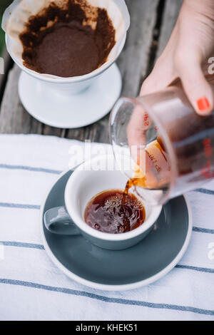 Köstliche, frisch gebrühten Kaffee in Gießen über Porzellan Kaffeetasse gießen Stockfoto