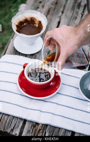 Köstliche, frisch gebrühten Kaffee im Freien in Porzellan rot Tasse gießen Stockfoto