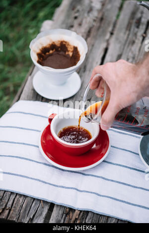 Köstliche, frisch gebrühten Kaffee im Freien in Porzellan rot Tasse gießen Stockfoto