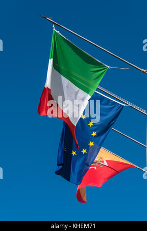 Italienisch, eu und sizilianischen Flaggen vor blauem Himmel hintereinander Fliegen von drei Fahnenmasten. Stockfoto