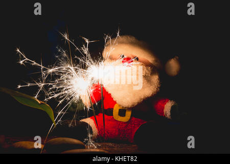 Santa Claus Doll auf Weihnachten auf dunklem Hintergrund mit Wunderkerzen. Stockfoto