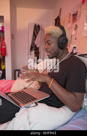 Junger Mann in Kopfhörer mit Musik auf seinem Laptop singen Stockfoto