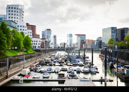 Bewölkter Tag im Düsseldorfer Hafen. Blick auf die Stadt auf den Medienhafen voller Boote Stockfoto