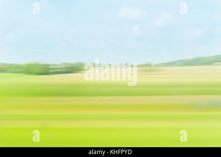 Zusammenfassung Hintergrund weichen, grünen und Stirn und blauen Tönen der Felder und die Landschaft aus fahrendem Zug Fenster Stockfoto