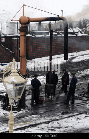 Personal warm zu halten durch das Feuer Teufel im Hof bei bridgnorth Schuppen. Severn Valley Railway. Stockfoto