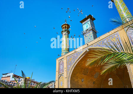 Die Herde der Tauben fliegen über dem Portal des Shah Moschee mit malerischen Minarette und die Clock Tower, Teheran, Iran. Stockfoto