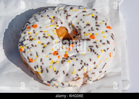 Große weiße iced Donut auf eine Papiertüte Stockfoto