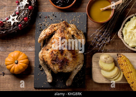 High-Angle Shot eines Truthahn auf einem rustikalen Holztisch neben einigen Schüsseln mit Soße, Kartoffelpüree, Heidelbeere Konfitüre, einige Scheiben von roaste Stockfoto