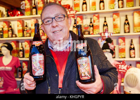 Hamburg, Deutschland. November 2017. Kioskverkäufer Tomasz Dudzek hält zwei Flaschen Glühwein und einen gebackenen Apfel mit frivolen Bildern an einem Stand auf dem Weihnachtsmarkt „Santa Pauli“ in Hamburg, 17. November 2017. Quelle: Georg Wendt/dpa/Alamy Live News Stockfoto