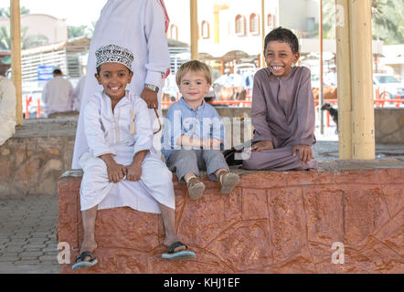 Nizwa, Oman, 10. Nobember 2017: omani Kid und Europäischen kid Hände schütteln Stockfoto