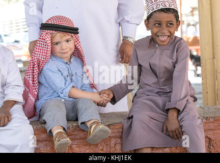 Nizwa, Oman, 10. Nobember 2017: omani Kid und Europäischen kid Hände schütteln Stockfoto