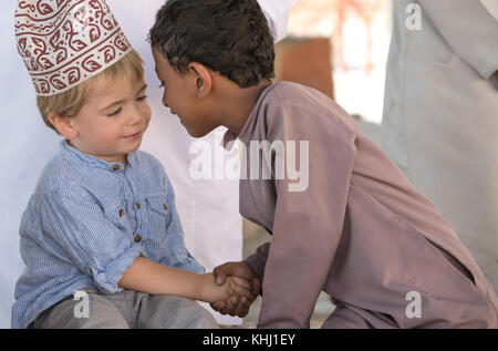 Nizwa, Oman, 10. Nobember 2017: omani Kid und Europäischen kid geben sich gegenseitig ein Eskimo kiss Stockfoto