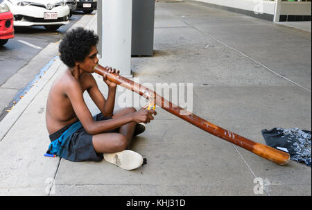 Junge Aborigines Junge spielt das Didgeridoo und Straßenmusik in der Street, Cairns, Far North Queensland, FNQ, QLD, Australien Stockfoto