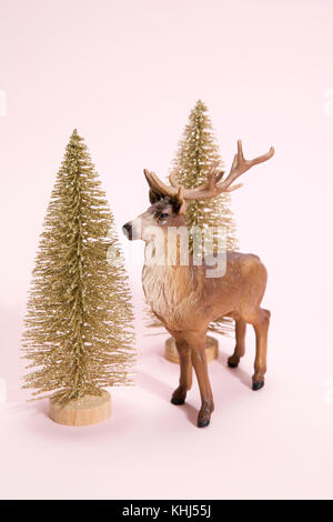 Goldenen Weihnachtsbaum mit Figurine Rentiere weiter, um es auf ein leuchtend rosa Farbe Hintergrund. Minimale still life Fotografie Stockfoto