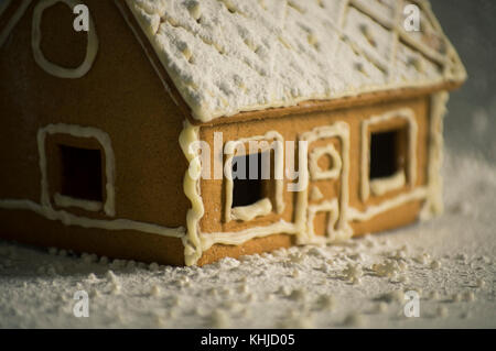 Gingerbread House in Winter Lights mit Puderzucker und Schneeflocken bedeckt. seichte Fokus Stockfoto