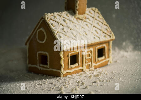 Gingerbread House in Winter Lights mit Puderzucker und Schneeflocken bedeckt. seichte Fokus Stockfoto