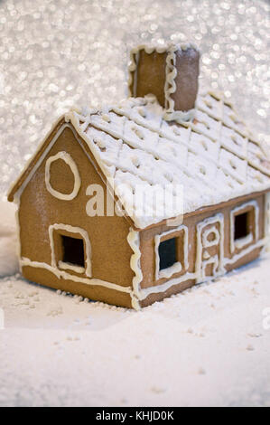 Gingerbread House in Winter Lights mit Puderzucker und Schneeflocken bedeckt. seichte Fokus Stockfoto