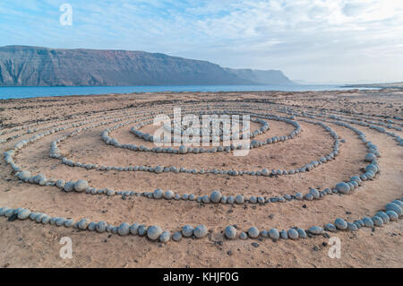 Runde Steine am Boden bildet eine Spirale, in der Nähe des Strandes, mit Lanzarote im Hintergrund, Caleta del Sebo, La Graciosa, Kanarischen Insel Stockfoto