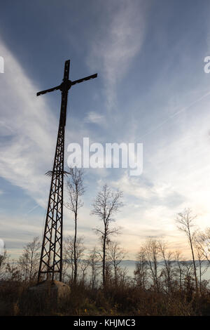 Ein hohes, Metall Kruzifix mit Bäumen und einige Nebel am Goldenen Stunde Stockfoto