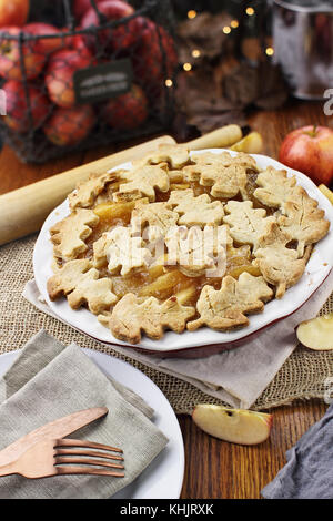 Frisch gebackenen Apfelkuchen mit oberen Kruste in autumn leaves Form. die Äpfel im Hintergrund. Stockfoto