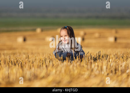 Happy 2 jähriges Mädchen zu Fuß in einer Sommer geernteten Feld Stockfoto