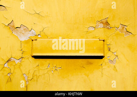 Retro alte gelbe Mailbox (Briefkasten) auf Risse, Grunge und Peeling Gelb gestrichene Wand im Freien montiert. Stockfoto