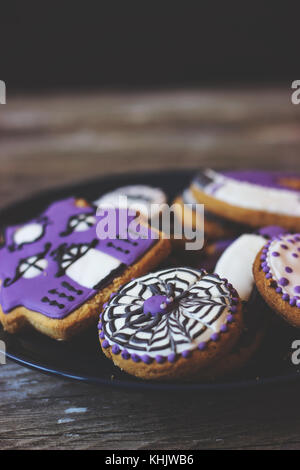 Royal icing Cookies - Platte dekoriert mit lila Cookies in verschiedenen Formen und Dekoration; auf hölzernen Tisch Stockfoto