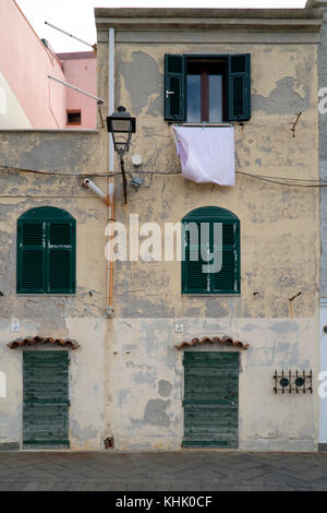 Street Scene von schmalen Häusern und Waschen an einem Fenster mit einer Straßenlaterne außerhalb Fensterläden, Sardinien. Stockfoto