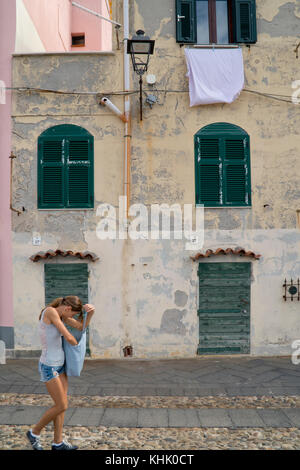 Street Scene von schmalen Häusern und Waschen an einem Fenster mit einer Straßenlaterne außerhalb Fensterläden, Sardinien. Stockfoto