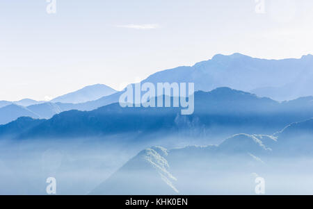 Dunstig blauen Berge von Zhushan in Alishan Erholungsgebiet in Taiwan durch Nebel bei Sonnenaufgang am Morgen bedeckt mit hellen Himmel. Stockfoto