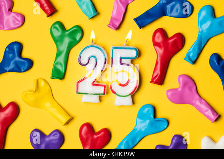 Nummer 25 Kerze mit Party Ballons auf einem gelben Hintergrund Stockfoto