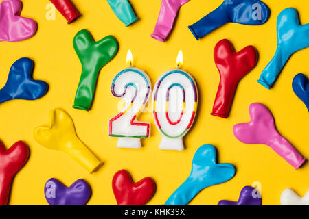 Nummer 20 Kerze mit Party Ballons auf einem gelben Hintergrund Stockfoto