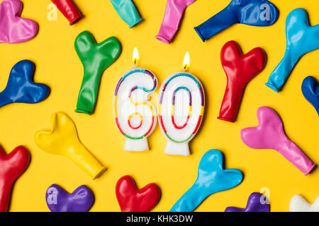 Nummer 60 Kerze mit Party Ballons auf einem gelben Hintergrund Stockfoto