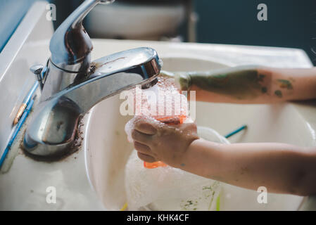 Ein Kleinkind Mädchen waschen Farbe weg die Hände in einem Waschbecken im Bad. Stockfoto