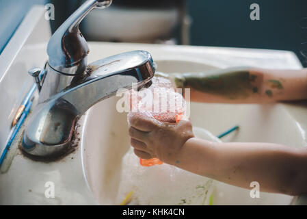 Ein Kleinkind Mädchen waschen Farbe weg die Hände in einem Waschbecken im Bad. Stockfoto