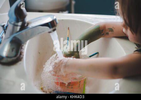 Ein Kleinkind Mädchen waschen Farbe weg die Hände in einem Waschbecken im Bad. Stockfoto