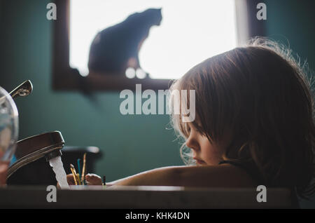 Ein Kleinkind Mädchen waschen Farbe weg die Hände in einem Waschbecken im Bad. Stockfoto