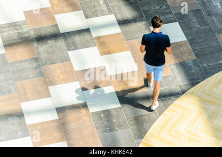 Silhouette der junge Kerl mit langen Schatten, die Aussicht von oben. Abstract background Blur in Bewegung Abbildung eines jungen Mannes in einem öffentlichen Gebäude Stockfoto