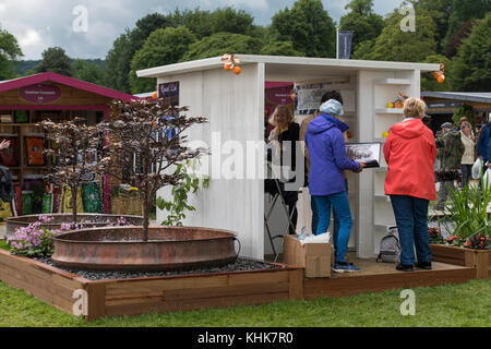 In der Nähe von Metall Skulptur Springbrunnen auf Quist Messestand mit Menschen arbeiten - RHS Chatsworth Flower Show Showground, Derbyshire, England, UK. Stockfoto