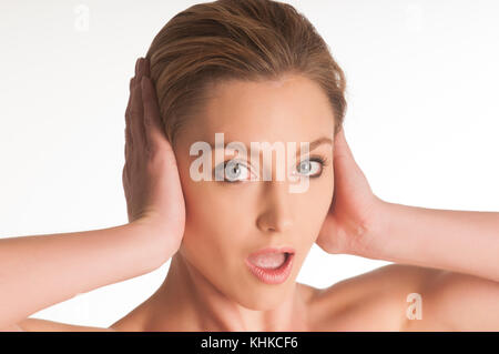 Schockiert, schöne junge blonde Frau Kopf in den Händen vor einem weißen Hintergrund Stockfoto